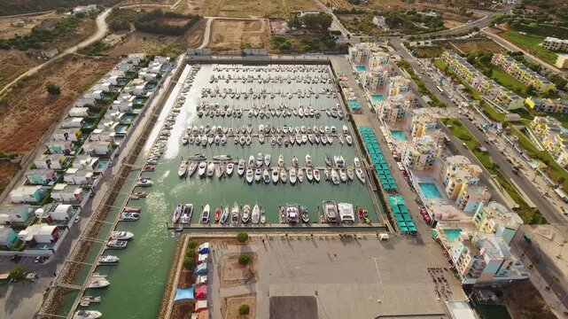 Stunning high altitude perspective of the albufeira marina, showing numerous yachts and boats docked in the harbor surrounded by colorful residential buildings on a sunny day in algarve, portugal