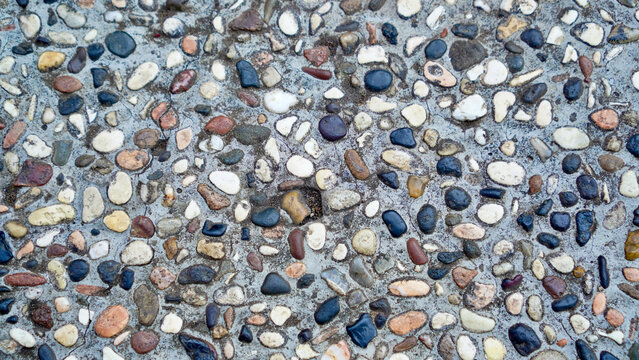 Top-down view of exposed aggregate concrete floor texture made of small colorful pebbles embedded in cement