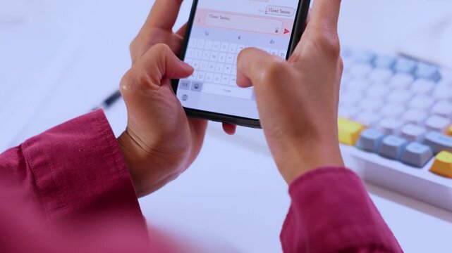 Mobile phone hand typing message on screen keyboard, communication technology with finger touch, smartphone close up near desk computer keyboard indoor digital office scene