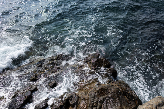 Waves crash on rocks by the shore during a sunny day at the beach