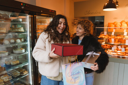 Two female friends holding gifts outdoors in the city