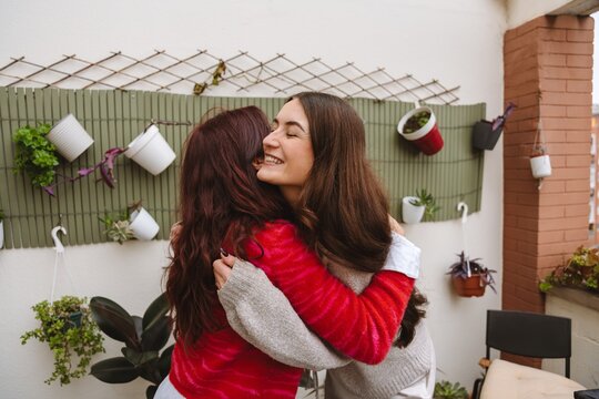 Two female friends greeting each other with a hug at a birthday party