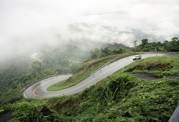 Obraz premium Nan folding curve scenic mountain road surrounded by lush green forest and misty hills in Nan, Thailand, famous travel destination, viewpoint, photography spot, winding route, nature landscape.