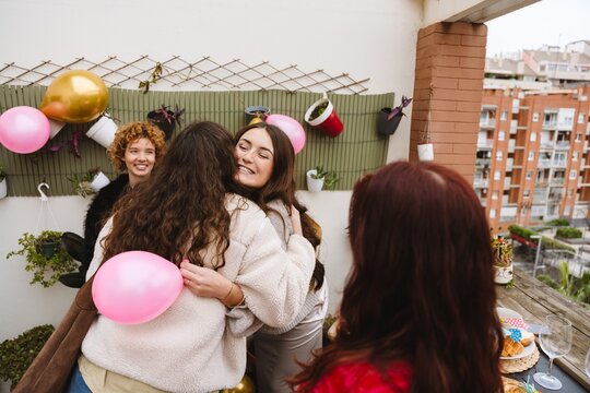 Group of female friends greeting each other with a hug at a birthday p