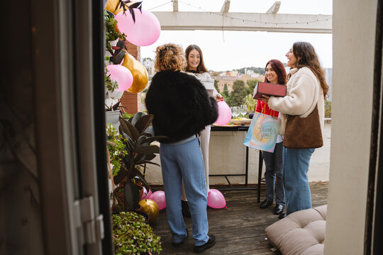 Group of female friends giving gifts at a birthday party on an apartme