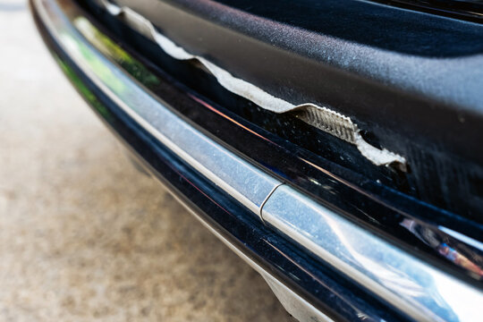Front bumper show torn, detached, peeling and broken lower rubber skirt lip or trim beneath under grille. Vehicle wear and tear,  Damaged front bumper and torn rubber lip of car. Loss of adhesion.