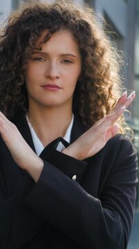 Dissatisfied Caucasian business woman crossing hands stop no negative attitude prohibit demonstrate disapprove disagree girl female businesswoman employer cross arms demonstrating reject sign in city