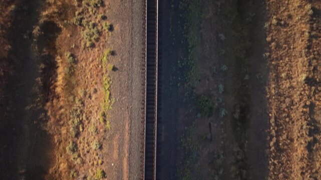 Straight down view while flying east and ascending above railroad tracks revealing Bogard Flat's golden meadow.  Lassen County, California.