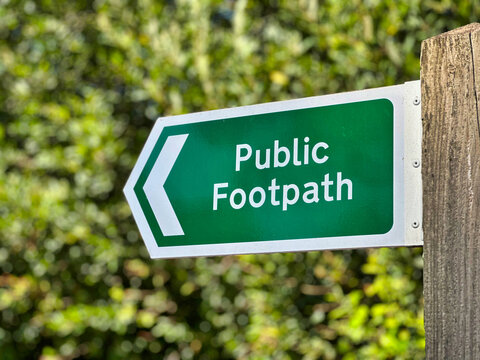 Green Public Footpath Directional Sign on Wooden Post in Countryside, UK