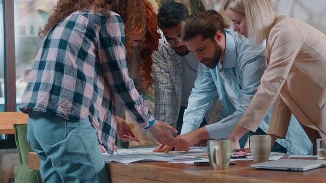 Casual informal business team designers architects emotional discussing blueprint building project plan in office five partners discuss talking job documents group architecture work process women men