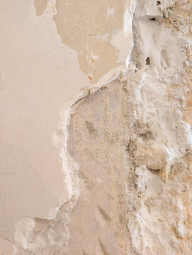 Exposed red brick wall with crumbling plaster and old pipes, raw architectural texture background with copy space.