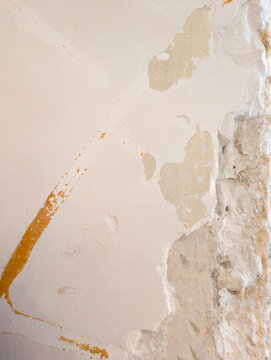 Exposed red brick wall with crumbling plaster and old pipes, raw architectural texture background with copy space.