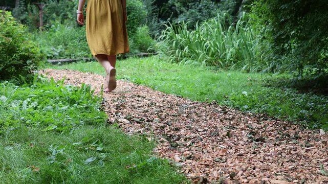 Woman walking on natural wood chip garden path. Sustainable landscaping, eco-friendly garden design and outdoor lifestyle