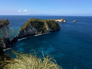 A scenic coastal view featuring rugged cliffs and clear blue waters. Lush greenery adds a touch of nature to the shoreline. Ideal for travel and nature themes. © mariiaplo