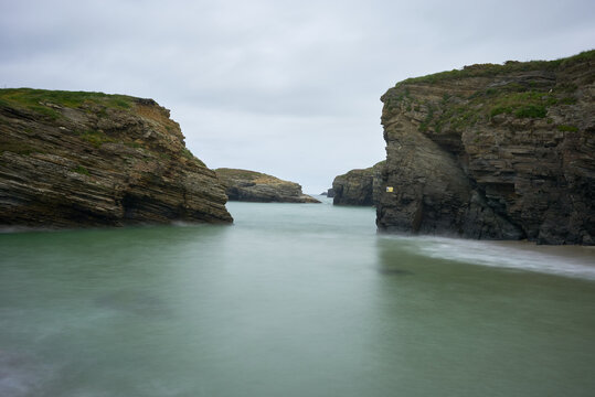 Moody long exposure of misty sea and rock at Praia das Catedrais, Beach of the Cathedrals in Ribadeo, Galicia Spain