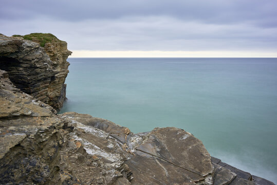 Moody long exposure of misty sea and rock at Praia das Catedrais, Beach of the Cathedrals in Ribadeo, Galicia Spain