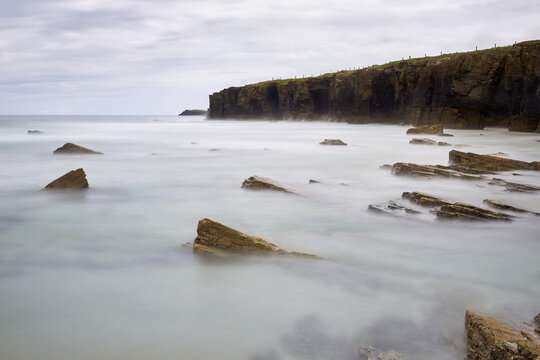 Moody long exposure of misty sea and rock at Praia das Catedrais, Beach of the Cathedrals in Ribadeo, Galicia Spain
