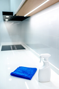 Detergent spray bottle and blue microfiber cloth on modern white countertop in domestic kitchen. Cleaning tool product for housework chores and home hygiene