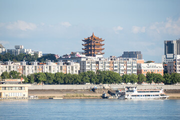 Naklejka premium A view of the historic Yellow Crane Tower standing above the modern city skyline and the river in Wuhan China on a clear sunny summer day