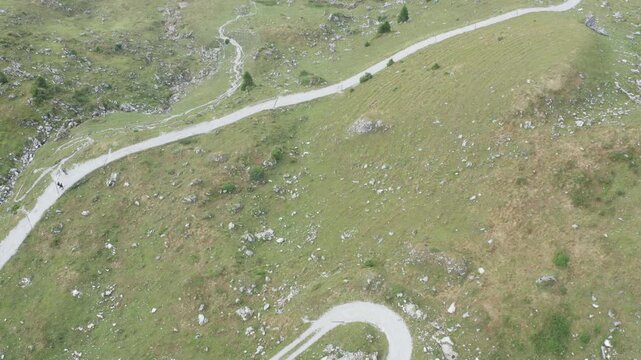 Aerial drone view in Gantrisch Nature Park tilting up from a hairpin bend on an alpine road over Gantrischseeli lake toward Selibuehl and the Swiss plateau, canton of Bern, Switzerland