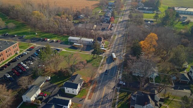 School buses arriving at an American school campus in autumn aerial drone view