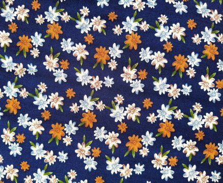 Seamless small floral Liberty style fabric pattern. Ditsy print with white, light blue and mustard orange daisy flowers with green leaves on a dark navy blue cotton background. Perfect for textile des