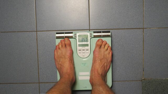 Individual stepping onto digital scale, observing weight change as feet transition from initial position to final reading, showcasing the journey of weight measurement and personal health awareness