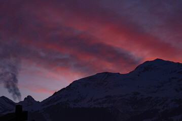 ンクと紫のグラデーションが広がる夕暮れ時、アルプスの山々とスイスの村落景観 © hirota