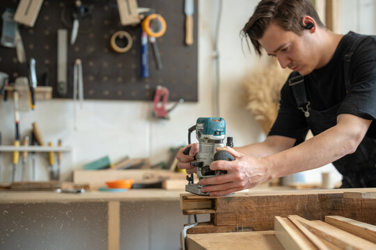 Working process of wooden item renovation in restoration workshop, carpenter using plunge router, processing wooden board with electric wood router machine instrument, reconstruction and craftsmanship
