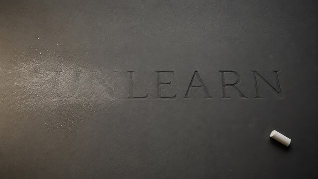 Unlearn word concept etched on dark slate blackboard with chalk dust