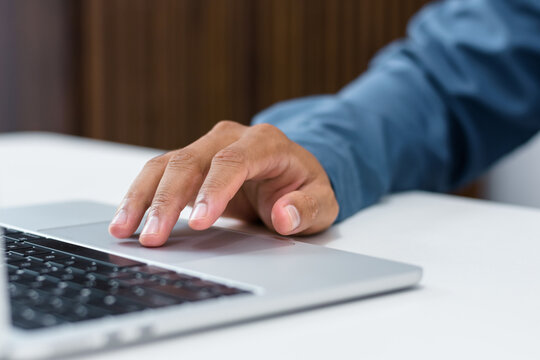Close up view of male businessman hand navigating laptop touchpad while working on corporate task at office workstation