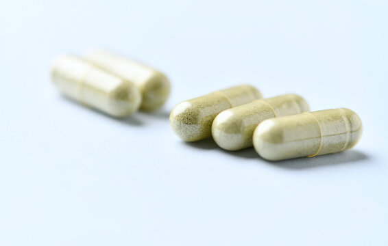 Barley grass capsules. Antioxidants. Concept for a healthy dietary supplementation. Bright background. Soft focus. Close up. Copy space.