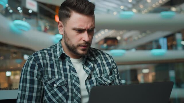 Disappointed troubled Caucasian businessman with laptop man upset online problem in business center frustrated male guy freelancer user with computer receive bad news email failure in shopping mall
