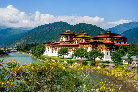 Bhutan, the Dzong of Phunakha situated next the river with it's pedestrian bridge and beautiful flowers.	