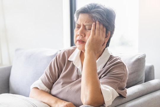 Sick, stress caucasians senior. Mature, adult elderly woman having migraine pain, headache symptom, feeling unhealthy, suffering from dizzy when sitting on sofa. Health care problems of older people.