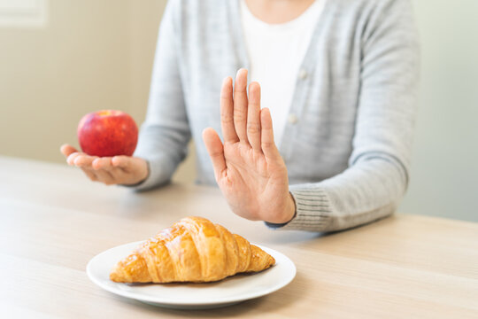 Ketogenic, Low carb, Intermittent Fasting Diet hand push out, refuse butter croissant bread on plate choose apple for good food, fighting to keep it from getting fat. Healthy nutrition of weight loss.