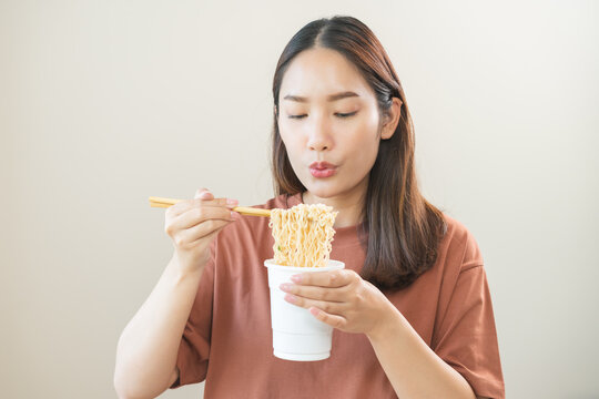 Happy temptation, attractive asian young student woman, cute girl using chopsticks eating instant ramen, noodles soup from a cup, cooking meal fast food lifestyle of traditional japanese person.