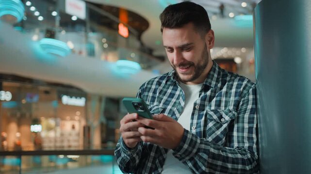 Optimistic Caucasian business man using mobile phone app smile internet communicating online indoors smile male smiling businessman with smartphone messaging with telephone network in shopping mall