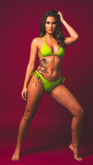Fototapeta premium Woman with dragon tattoo poses in bright green bikini