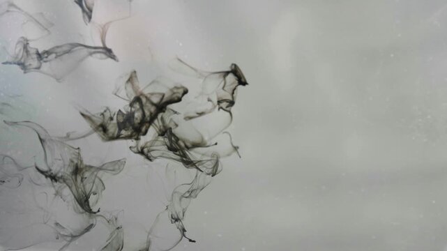 Macro shot of black ink pouring and splashing in clear water