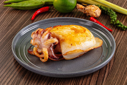 Grilled cuttlefish on gray plate with chili lime and herbs