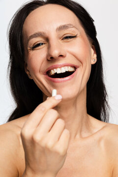 Optimistic woman holding pill for health and wellness