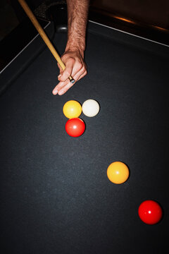 Player Aims at Pool Balls on a Black Felt Table During a Game