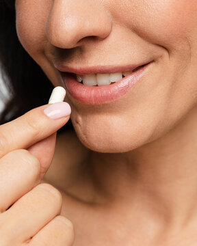 Positive woman taking white capsule supplement for health