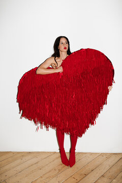 Woman holding large red fringed heart expressing love