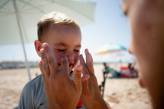 Child getting sunscreen applied protecting young skin on beach