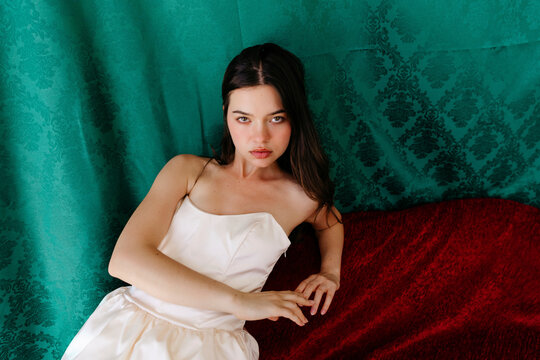 Elegant young woman posing with rich fabrics background