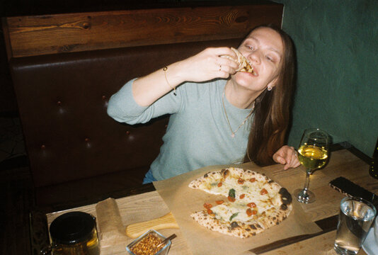 Woman Enjoys Pizza at a Restaurant 