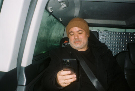 Man Sitting in Vehicle Looking at Phone