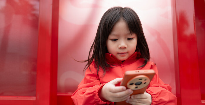 Child Interacts With Smartphone in Bright Red Setting